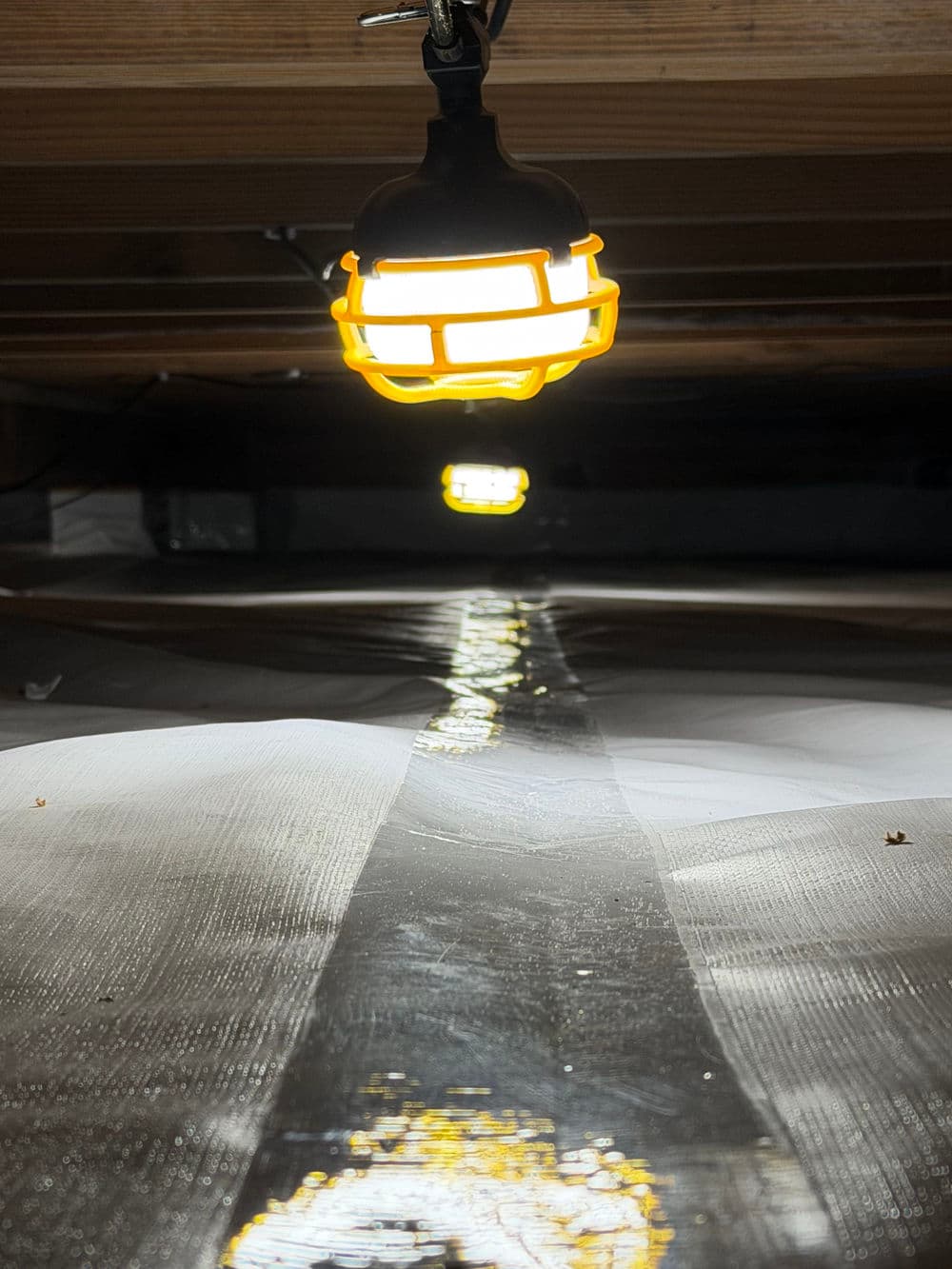 Bright yellow work lights illuminating a tarp-covered surface in a dark, enclosed space.